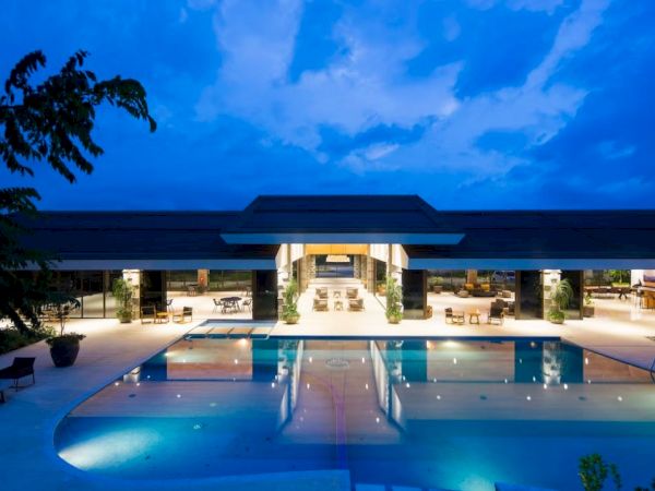 A luxurious pool area in front of an upscale building, beautifully lit with a deep blue sky above, providing a serene evening ambiance.