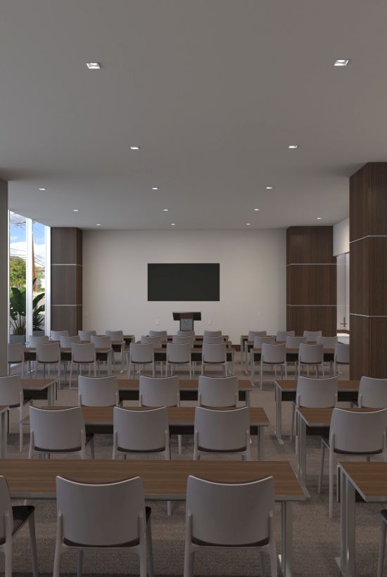 A modern conference room with rows of chairs, tables, a large screen at the front, and large windows letting in natural light.