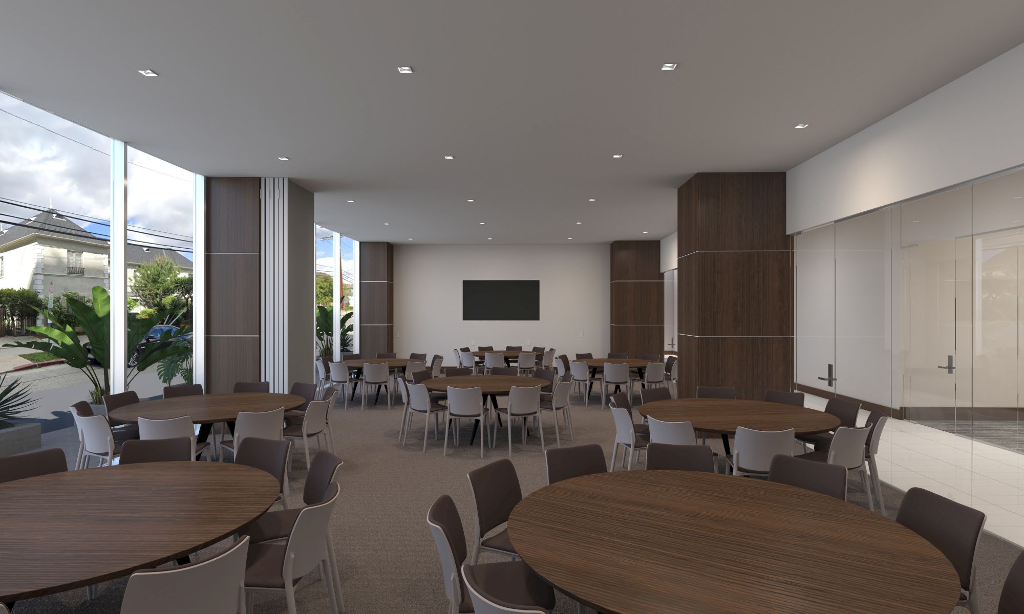 The image shows an empty conference room with round tables, chairs, a large screen, and modern decor, with windows allowing natural light.